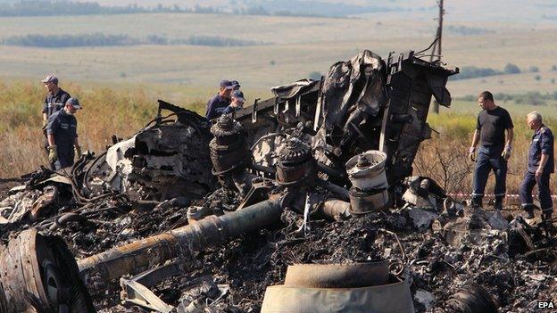 Ukrainian workers inspect debris at the main crash site of the Boeing 777 Malaysia Airlines flight MH17 on 20 July 2014