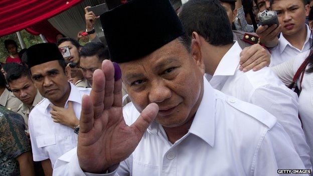 Indonesian presidential candidate Prabowo Subianto waves with an ink-stained finger after voting in his local polling station on 9 July, 2014 in Bojong Koneng, Indonesia