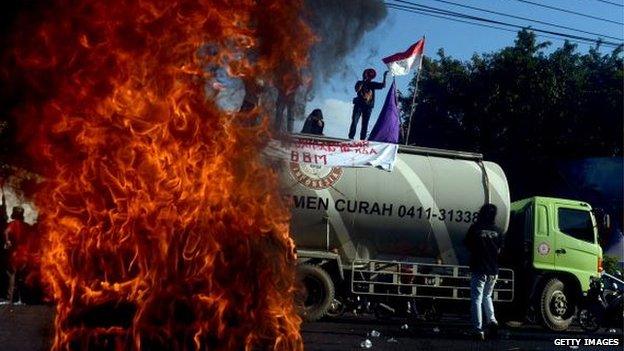 Demonstrators burn tyres near a cement truck during a May Day rally outside the local parliament of Makassar city in Sulawesi island on 17 June, 2013