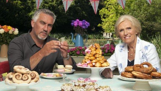 Paul Hollywood and Mary Berry at a table piled high with cakes