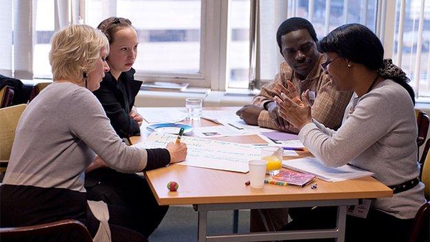 Four people having training, sitting around a table with paper and pens