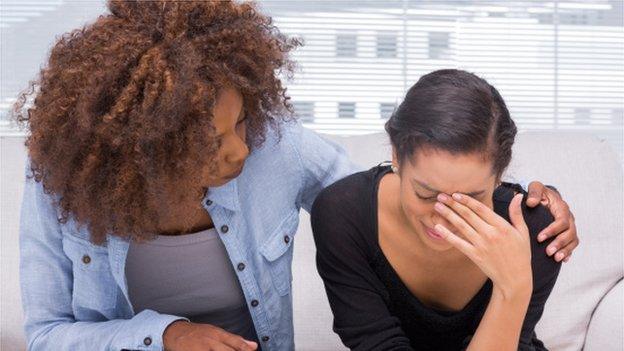 A woman crying with another woman comforting her