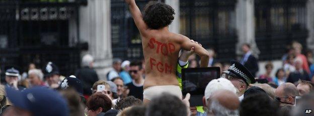 A woman protesting outside Westminster with 'Stop FGM' written on her back