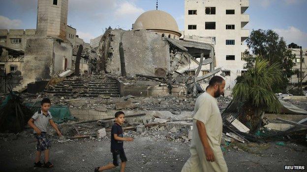 Palestinians walk past a ruined mosque in the Gaza Strip