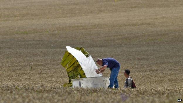 A man taking a picture of a piece of aircraft wreckage in a field