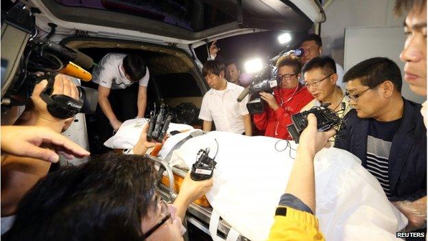 Policemen transport a stretcher with a body believed to be that of Yoo Byung-un, who headed the family that owned the operator of a ferry that capsized in April, killing more than 300 people, into an ambulance at a hospital in Suncheon on 22 July 2014.