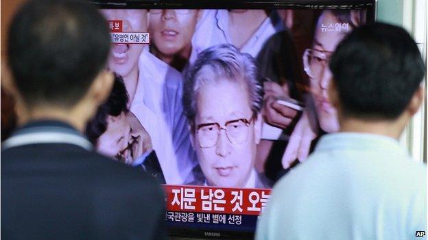 People watch TV news showing Yoo Byung-eun, the fugitive owner of the sunken ferry Sewol, at Seoul Railway Station in Seoul, South Korea, Tuesday, 22 July 2014.