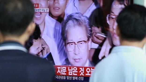 People watch TV news showing Yoo Byung-eun, the fugitive owner of the sunken ferry Sewol, at Seoul Railway Station in Seoul, South Korea, Tuesday, 22 July 2014.