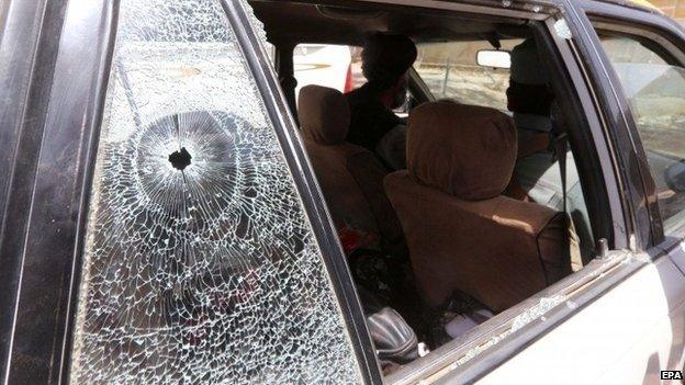 Afghan security officials inspect a car, after unknown gunmen opened fire on the car, in Herat, Afghanistan, 24 July 2014.