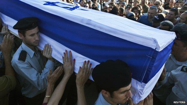 A mourner touches the flag-draped coffin of Israeli soldier Natan Cohen, killed during fighting in Gaza on Tuesday, during his funeral in Modi"in, a town between Jerusalem and Tel Aviv, July 23, 2014.