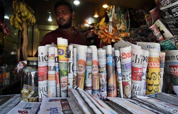 Indian newspapers with front pages featuring opposition leader Narendra Modi are on display at a stall in Bangalore, India, Saturday, May 17, 2014.