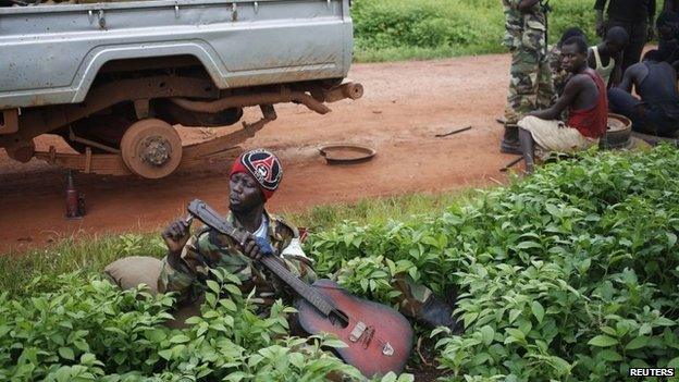 A Seleka fighter adjusts a broken guitar in a village between Bambari and Grimari in CAR on 31 May 2014