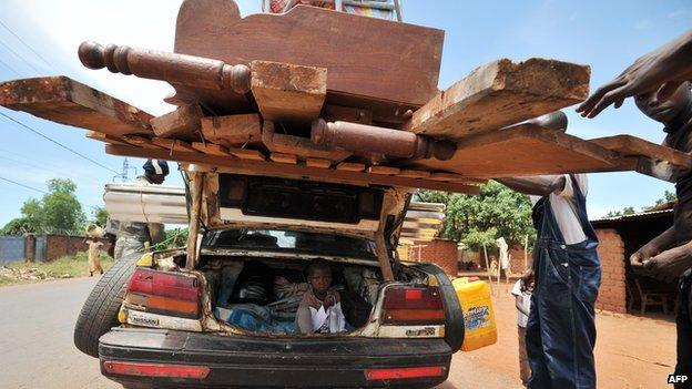 Men check a loaded car, in which trunk a young girl is seated, at an anti-balaka checkpoint in Bangui on 1 March 2014