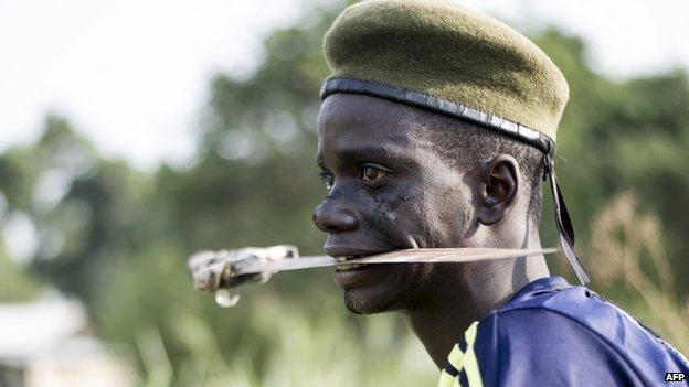 A member of the anti-balaka militia holds a blade in his mouth as he trains in the Boeing neighbourhood of Bangui, Central African Republic, on 24 February 2014