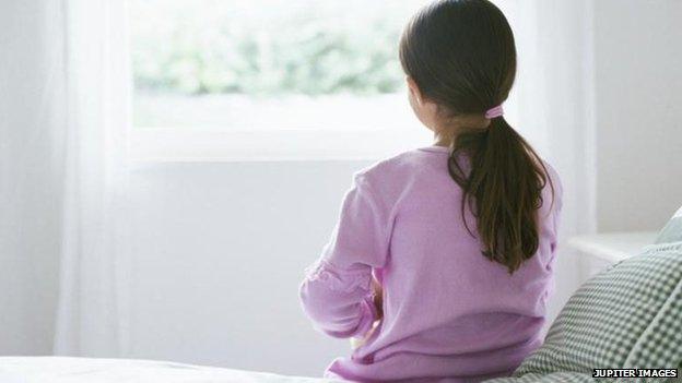 Young girl sitting on bed