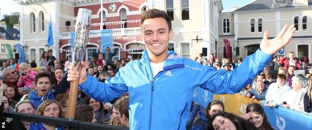 Tom Daley carries the Commonwealth Games Baton as it arrives into St Aubans harbour, Jersey