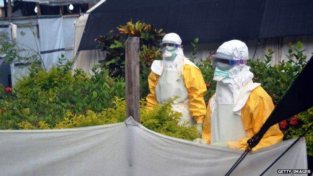 Members of Doctors Without Borders (MSF) wearing protective gear walk outside the isolation ward of the Donka Hospital, on 23 July 2014 in Conakry