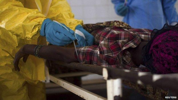 Medical staff take a blood sample from a suspected Ebola patient at the government hospital in Kenema, Sierra Leone, 10 July, 2014.