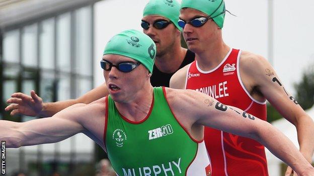 Conor Murphy of Northern Ireland waits to take over from Aileen Reid of Northern Ireland as Jonathan Brownlee of England looks on in the Triathlon Mixed Team event