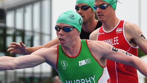 Conor Murphy of Northern Ireland waits to take over from Aileen Reid of Northern Ireland as Jonathan Brownlee of England looks on in the Triathlon Mixed Team event