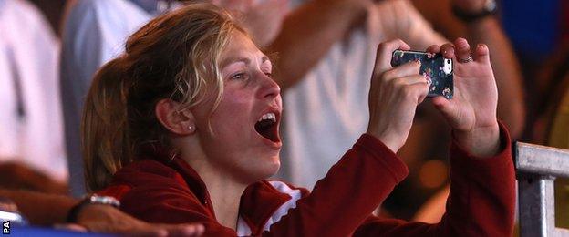 Gemma Gibbons takes photos of her husband, Scotland"s Euan Burton receiving his gold medal