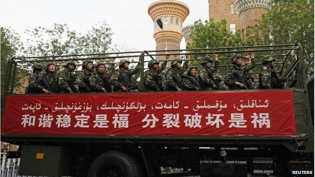 Paramilitary policemen stand on a truck as they travel past the Xinjiang International Grand Bazaar during an anti-terrorism oath-taking rally in Urumqi, Xinjiang on 23 May 2014.