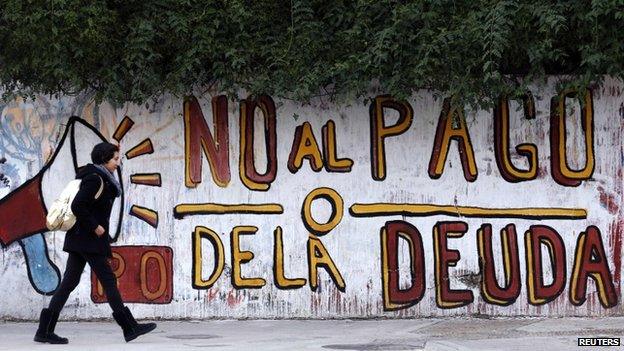 Woman walks past a graffiti that reads "No to the debt payment" in Buenos Aires, 28 July 2014