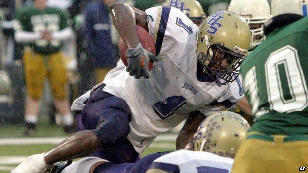 Bloomington High School running back Adrian Arrington tries to clear a pile of Providence Catholic defenders during the Class 6A championship football game in Champaign, Illinois 27 November 2004