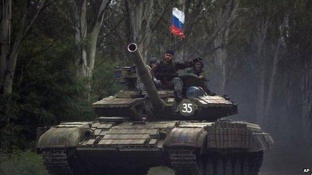 Pro-Russian rebels ride on a tank flying Russia's flag, on a road east of Donetsk, Monday