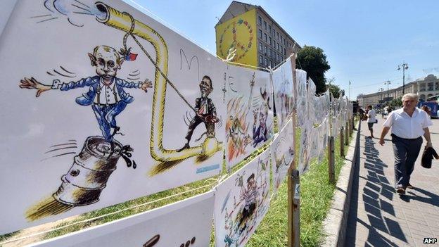 A man walks past caricatures of Russian President Vladimir Putin at an open-air exhibition by Ukrainian cartoonist, architect and journalist Oleh Smal, in the center of Kiev on 29 July 2014.