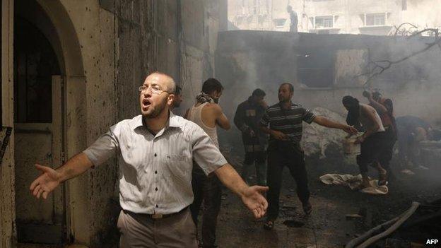 Palestinians try to put out a fire in Gaza City after an Israeli air strike, 30 July