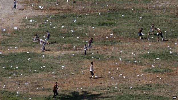 Palestinians gather leaflets dropped by an Israeli plane warning residents of Gaza City, 30 July