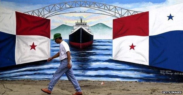 Man walking past mural of panama flag