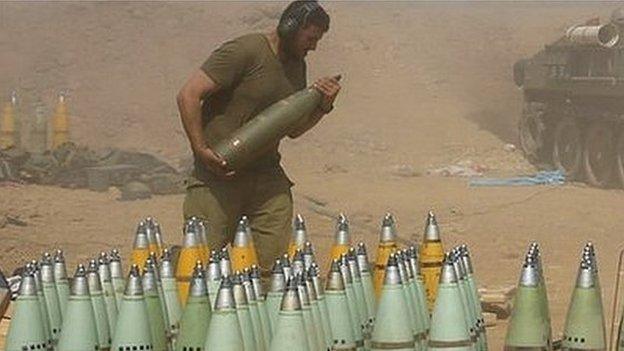 An Israeli soldier carries a shell at a mobile artillery unit while it fires towards the Gaza Strip