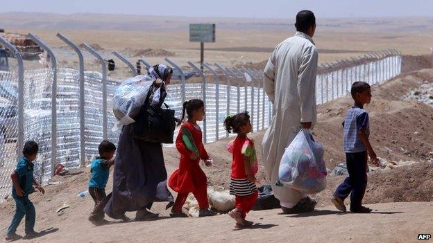 Members of an Iraqi displaced family, who fled violence in the northern city of Tal Afar, carry bags as they arrive at Khazer refugee camp near the Kurdish checkpoint of Aski kalak, 40 km West of Arbil, the capital of the autonomous Kurdish region of northern Iraq on July 27, 2014