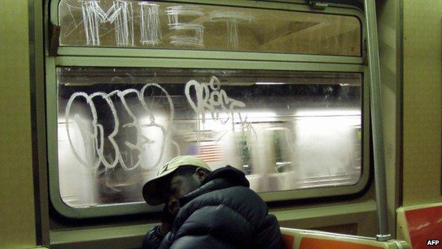 A man sleeps next to scratchiti on a window