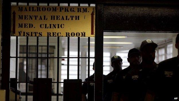 Prison guards at Rikers Island walk past a sign for the mental health clinic