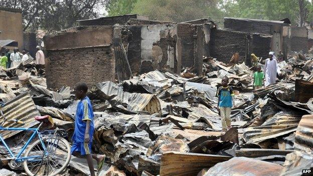 A boy walks past burnt shops at Ngumborum central market on 11 May 2014 at Ngala in Gamboru Ngala district, Borno State