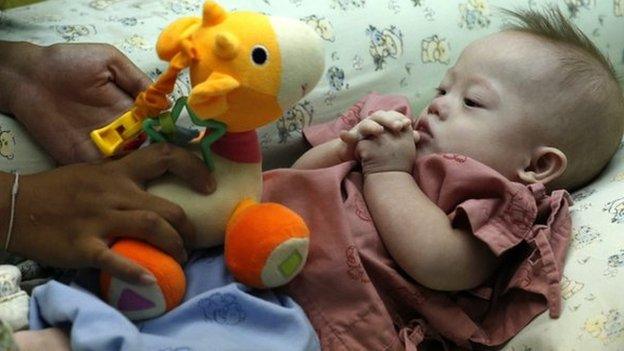 A Thai surrogate mother, Pattharamon Chanbua (not seen), 21, plays with her seven-month-old Down's Syndrome baby, Gammy at a hospital in Chonburi province, Thailand, 4 August 2014.