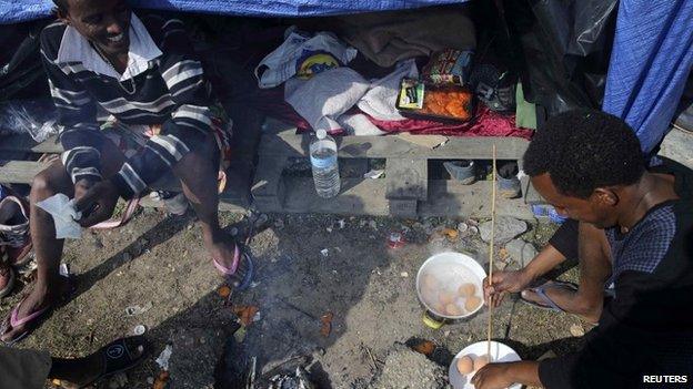 An Eritrean migrant cooks eggs outside his shelter in the "jungle" close to a chemical factory in Calais