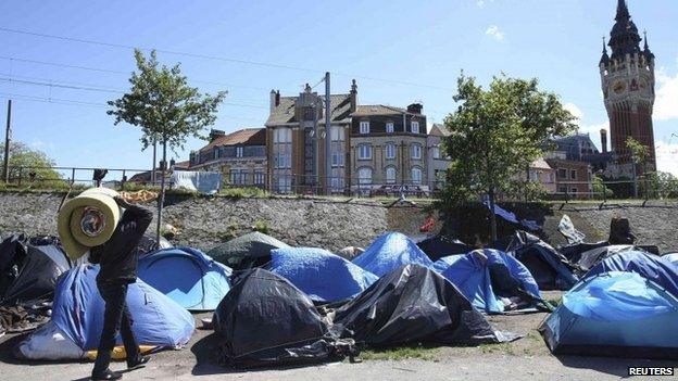 An African migrant carries a foam mattress in a tent camp close the city hall in Calais