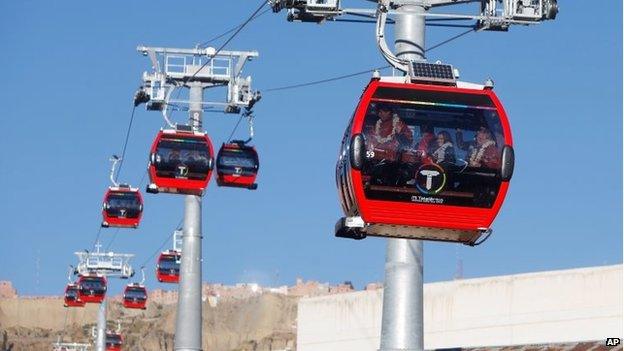 President Evo Morales waves from inside the cable car on the right, during the inauguration ceremony in La Paz