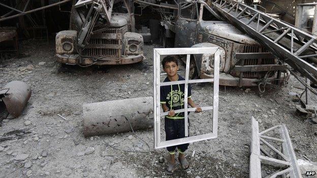 A Palestinian youth holds a window frame as he inspects a destroyed building in the Al-Shejaea neighbourhood of Gaza City