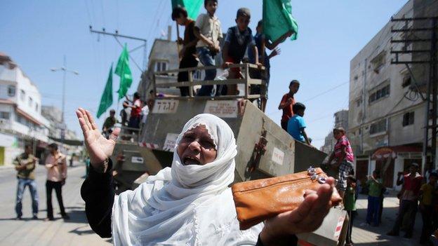 Palestinian woman gestures in front of Israeli military equipment, which witnesses said was left behind by Israeli forces during a ground offensive, in Khan Younis in southern Gaza Strip