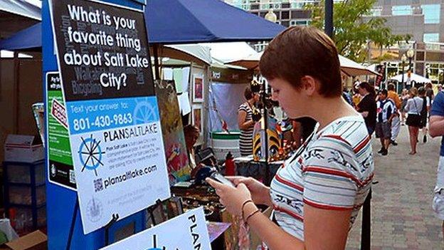 Woman texting in front of a sign