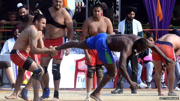 A Sierra Leone kabaddi player (R) is tackled by a British opponent during the 4th World Cup Kabaddi Punjab 2013