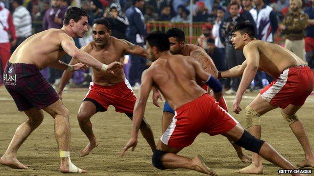 A Scotland player (L) attempts to tag his Canada opponent during the 4th World Cup Kabaddi Punjab 2013 tournament