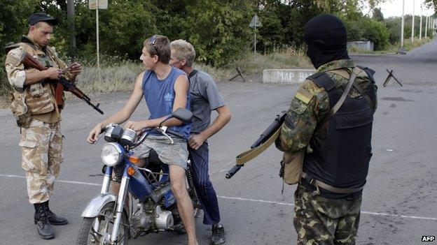 Ukrainian troops inspect documents at a checkpoint