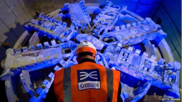 Crossrail construction worker stands next to a tunnel boring machine