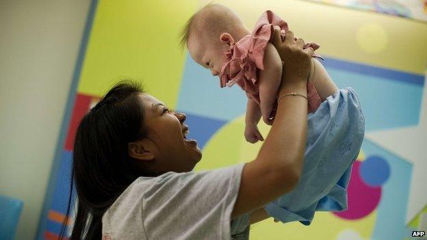 Thai surrogate mother Pattaramon Chanbua (left) with her baby Gammy, born with Down's Syndrome, at the Samitivej hospital, Sriracha district in Chonburi province, 4 August 2014